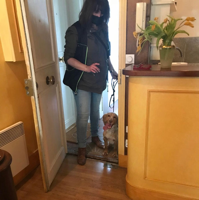 A woman standing in a doorway with a bedbug sniffing dog.